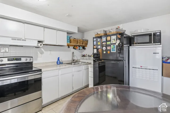 Kitchen featuring white cabinetry, light-toned countertops, a stainless steel range, and tile flooring