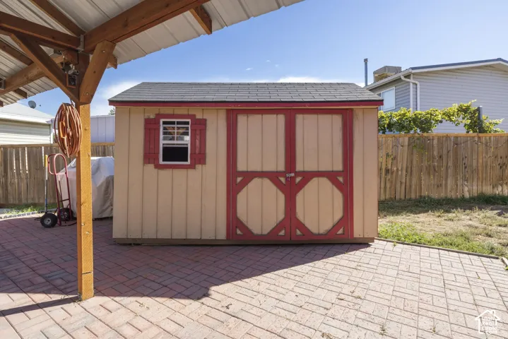 Red brick paver patio with a wood-framed overhead structure and metal roof