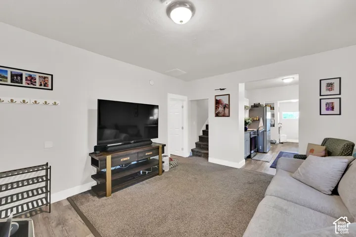 Open-concept living space featuring wood-finish flooring, recessed lighting, and an archway leading to a kitchen area