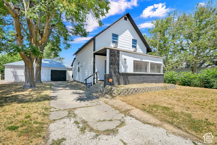 Two-story white exterior with black trim, concrete driveway, and established trees