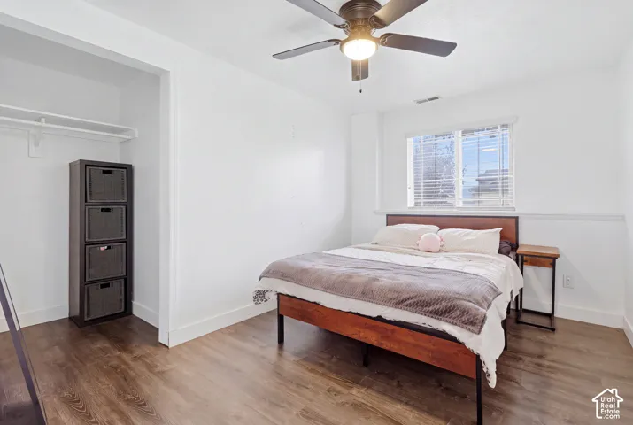 Wood-finish flooring, ceiling fan with integrated lighting, white walls, and a window with blinds