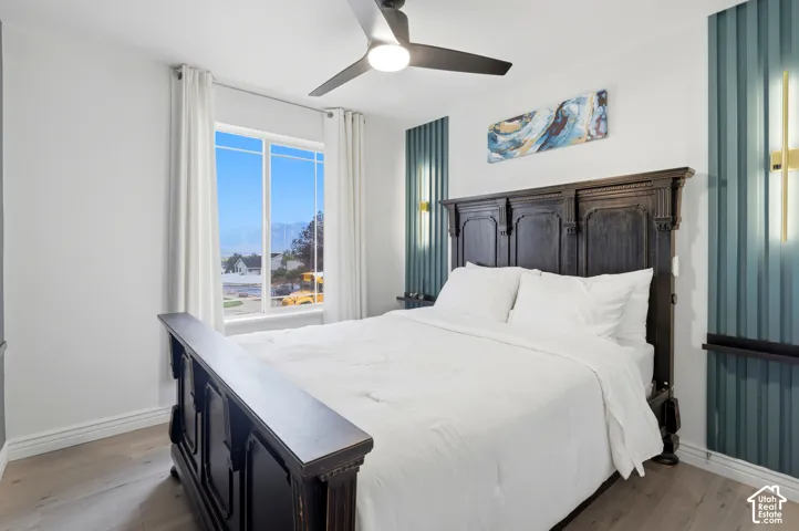 Bright room with a large multi-pane window, wood-finish flooring, and a ceiling fan