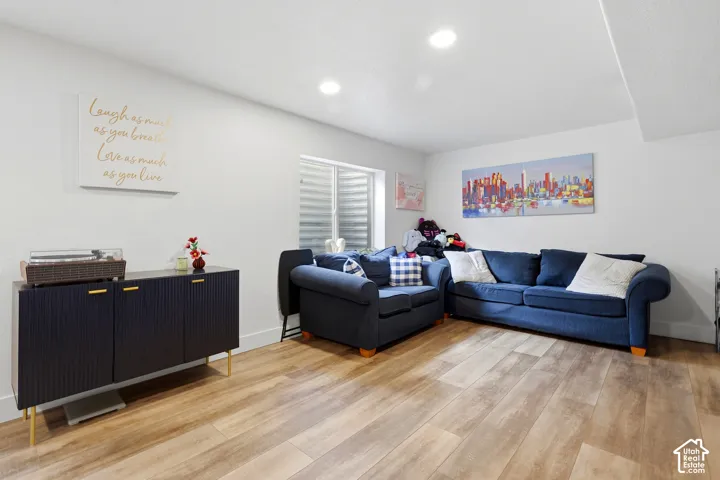Recessed lighting illuminates the space, featuring wood-finish flooring and a window with horizontal blinds