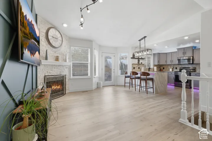 Light wood-finish flooring throughout, complemented by a gas fireplace with a white stone surround and mantel