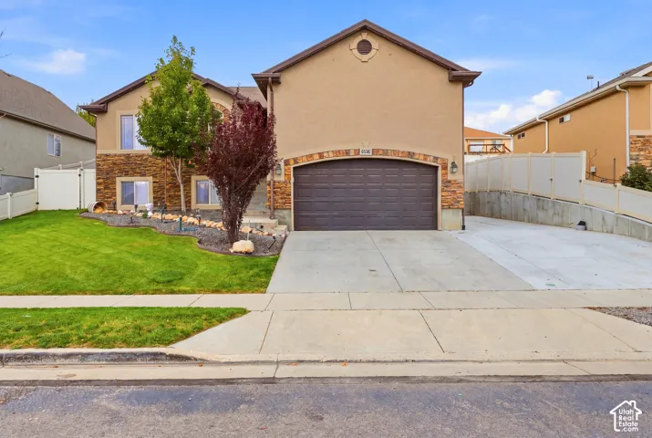Charming two-story home featuring a stucco and brick exterior with an arched entryway, two-car garage with dark paneled door, and a wide concrete driveway