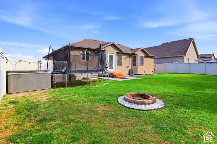 Expansive backyard with a fire pit, hot tub, and wood deck