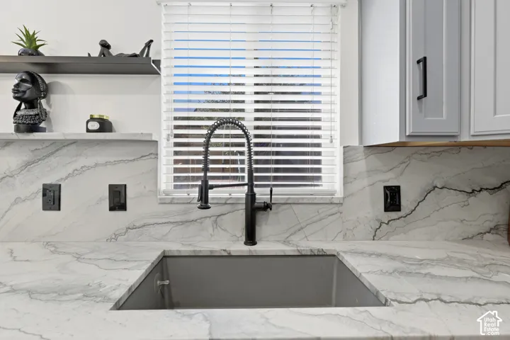 Integrated sink with a matte black pull-down faucet, light-toned countertop with distinct veining, coordinating backsplash, and white cabinetry with dark hardware