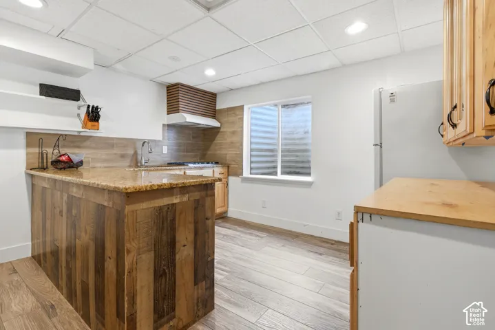 Kitchen featuring wood-finish flooring, granite countertops, wood-paneled island, and recessed lighting
