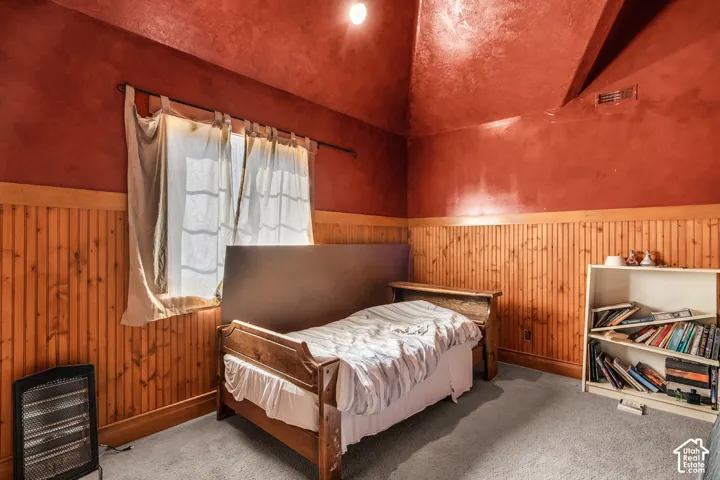 Accent wall paneling, red textured walls, and carpeted flooring