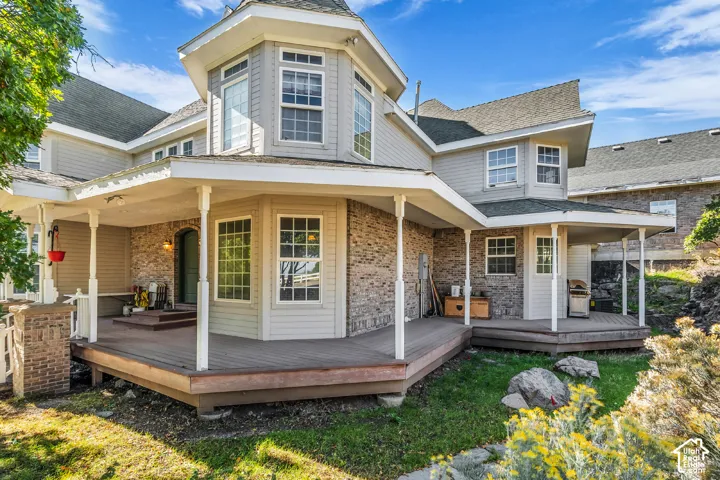 Multi-level deck with covered porch areas, bay window, and stone accent siding