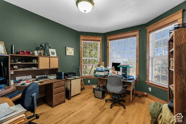 Hardwood flooring, painted walls, three large windows, and a built-in wood finish desk with shelving