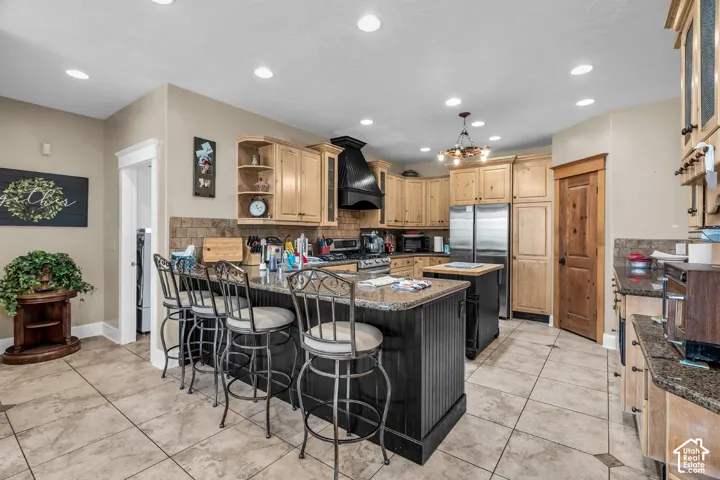 Kitchen featuring wood cabinetry, an island with countertop seating, stainless steel appliances, and tile flooring