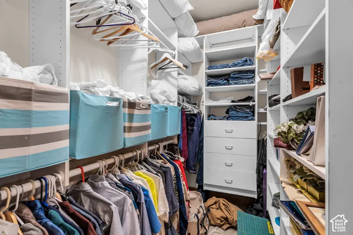Custom closet system with white shelving, multiple hanging rods, and built-in drawers