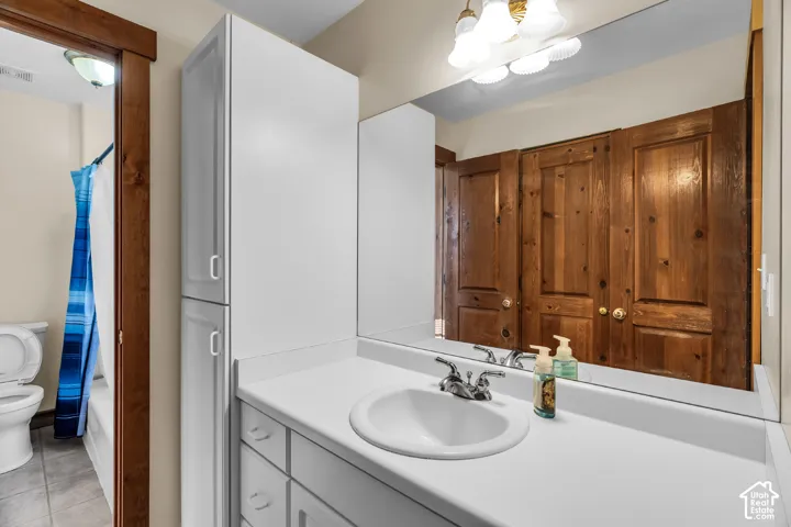 White vanity with an integrated sink and chrome faucet, large wall-mounted mirror, and overhead vanity lighting