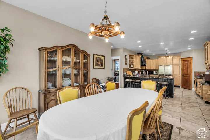 Dining area with a wagon wheel chandelier, wood-finish hutch, and tiled flooring