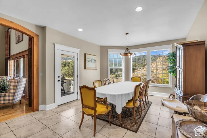 Bay window with multiple large glass panes, recessed ceiling lighting, a glass-paneled door, tile flooring, and a decorative archway