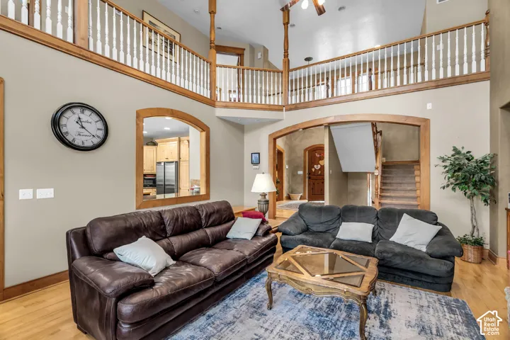 Two-story living area with hardwood flooring, a vaulted ceiling, and a second-story interior balcony with wood railings
