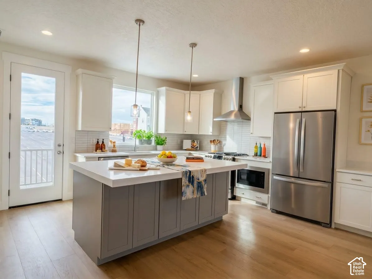 Gourmet kitchen featuring a central island with countertop seating, wood-finish flooring, stainless steel appliances, and white shaker cabinetry