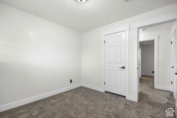 Neutral wall paint, textured ceiling, paneled interior doors with matte black hardware, and gray carpet flooring