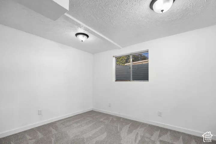 Wall-to-wall carpeting with a geometric pattern, neutral painted walls, recessed window, and flush-mount ceiling lighting