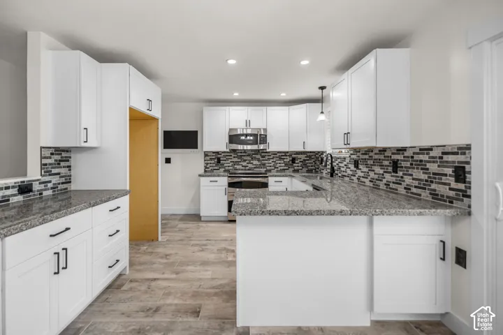 Modern kitchen featuring white shaker-style cabinetry, granite countertops, and a multi-tonal tile backsplash