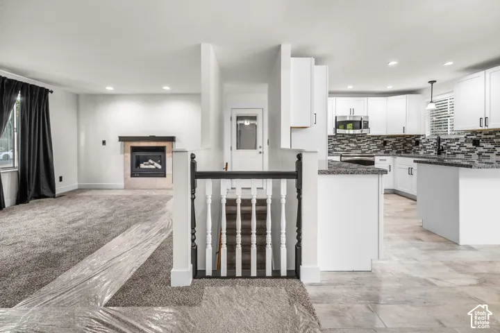 Kitchen featuring white cabinetry, granite countertops, and a mosaic tile backsplash