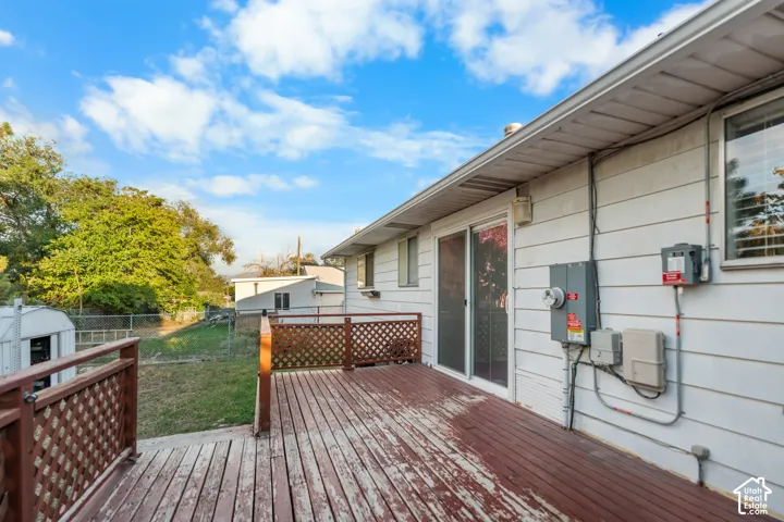 Expansive rear deck with lattice railing, slider door access, and a chain link fence enclosing the yard