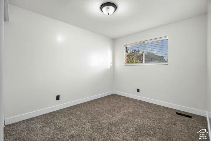 Neutral color palette, window with horizontal blinds, flush mount ceiling light, and wall-to-wall carpeting