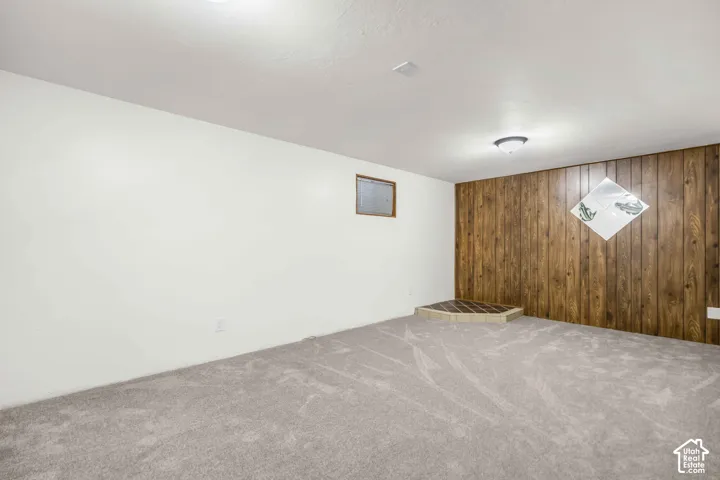 Textured carpeting, wood-paneled accent wall, and a tiled platform