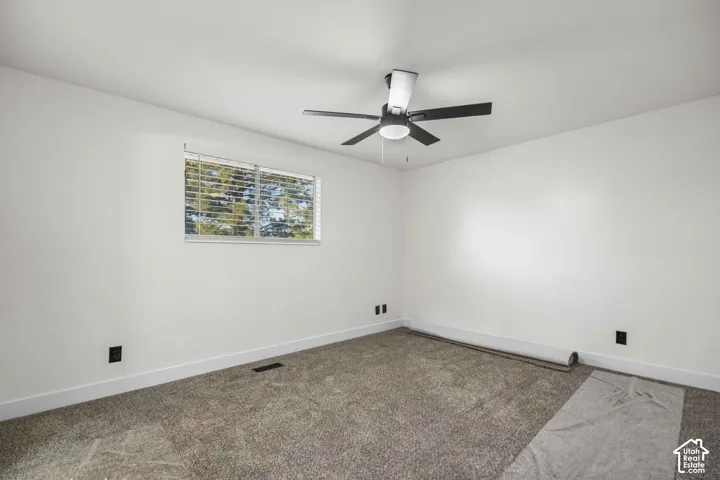 Recessed window with horizontal blinds, overhead ceiling fan with light, and neutral-toned wall-to-wall carpeting