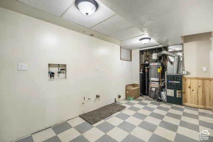 Utility area with checkerboard tile flooring, drop ceiling, and flush mount lighting