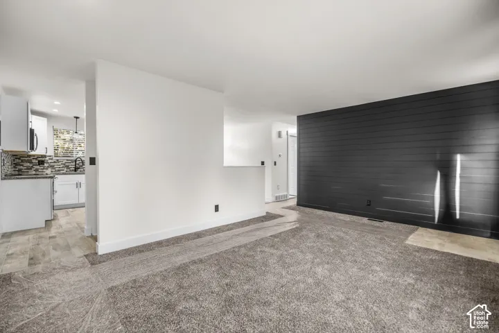 Spacious room with gray carpet flooring and a dark shiplap accent wall
