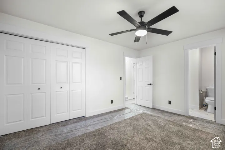 Spacious room featuring neutral carpeting, a modern ceiling fan, and white bi-fold closet doors with black hardware