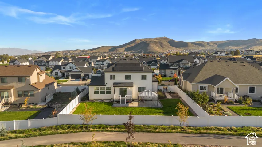 Expansive backyard featuring a manicured lawn, white privacy fencing, and a paved patio area