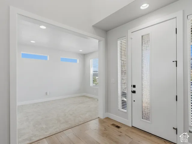 Recessed lighting, wood-finish flooring, full-light entry door with privacy glass, sidelights with blinds, and transom windows