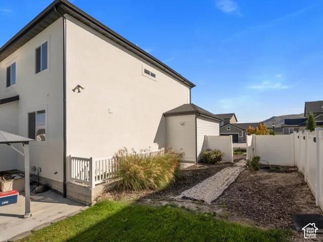 Stucco exterior with multiple windows, black gutters, and a white privacy fence