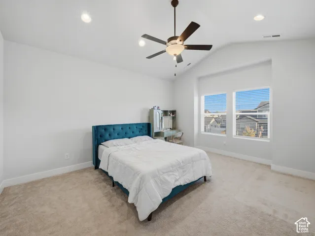 Vaulted ceiling with recessed lighting and a ceiling fan, two windows, and neutral carpeting