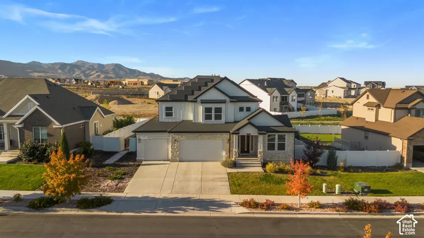 Modern farmhouse-style exterior with a stone and board-and-batten facade, dark shingle roof, attached two-car garage, and a concrete driveway