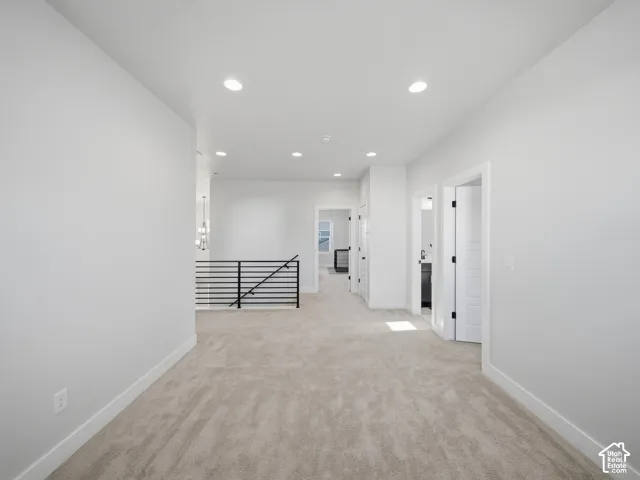 Open landing featuring neutral carpeting, recessed lighting, white walls, and a black metal railing