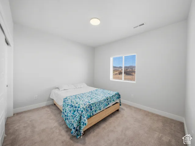 Neutral-toned wall-to-wall carpeting, white walls, window with blinds, and a flush-mount ceiling light