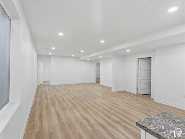 Expansive open-concept room featuring recessed lighting, wood-finish flooring, white walls, and a visible partial counter surface