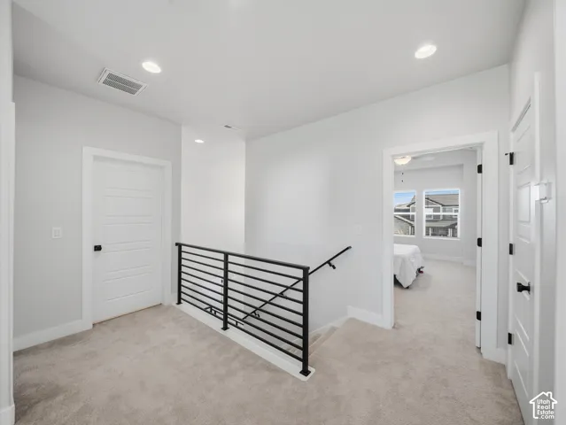 Carpeted landing featuring recessed lighting, a modern horizontal bar railing, and white paneled doors with matte black hardware