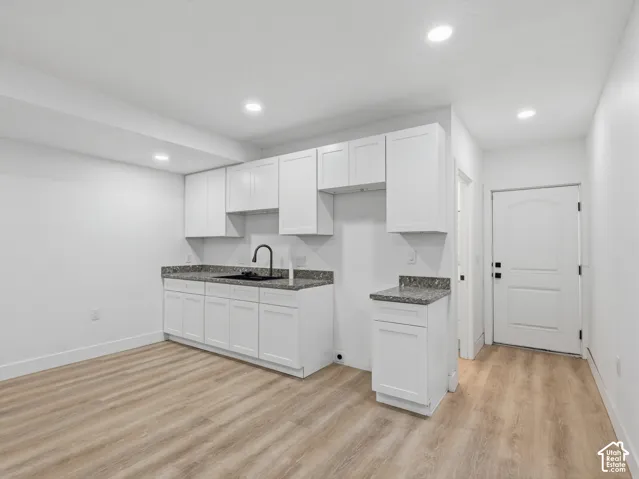 White cabinetry with dark countertops, wood-finish flooring, and recessed ceiling lights