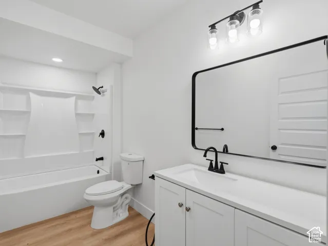 White vanity with integrated sink, black fixtures, and wood-finish flooring