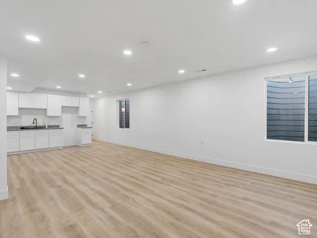 Open-concept living area featuring wood-finish flooring, recessed lighting, and white walls