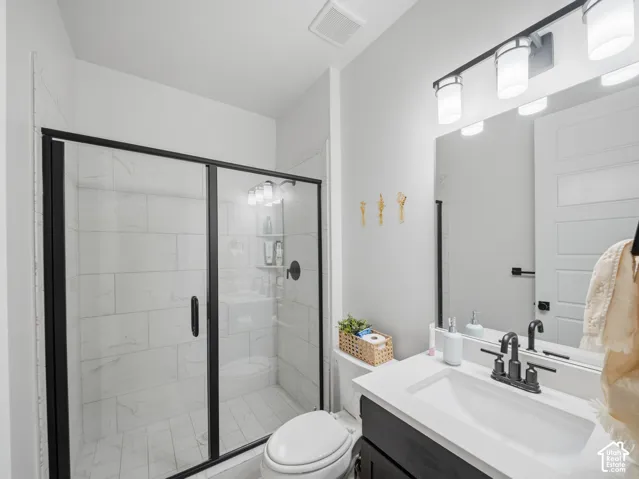 Spacious walk-in shower with black-framed glass enclosure, white tile surround, and matte black fixtures