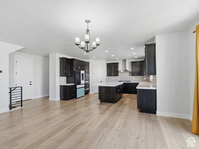 Open-concept kitchen featuring dark wood cabinetry, white countertops, a central island, stainless steel appliances, and wood-finish flooring