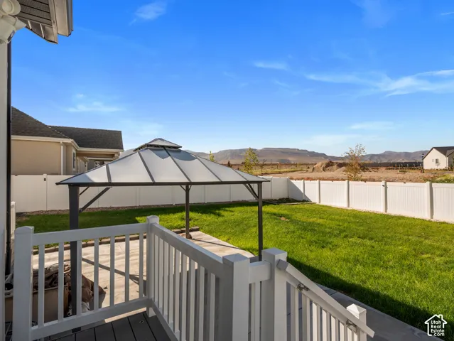 Deck with white railing, covered patio structure, lush green lawn, and privacy fencing