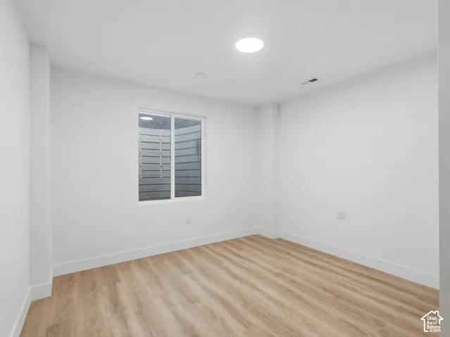 Recessed ceiling lighting, wood-finish flooring, and white walls