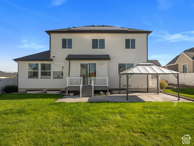 Expansive backyard featuring a lush lawn, concrete patio, and a covered gazebo